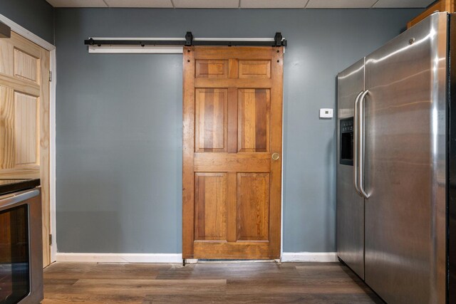 kitchen featuring stainless steel refrigerator with ice dispenser, a paneled ceiling, baseboards, and dark wood finished floors
