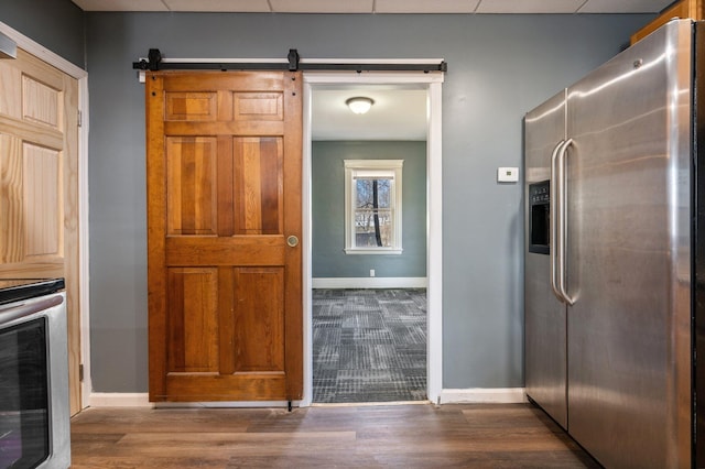 kitchen featuring wood finished floors, stainless steel refrigerator with ice dispenser, and baseboards