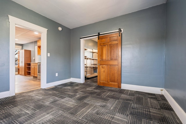 interior space featuring a barn door, carpet flooring, and baseboards