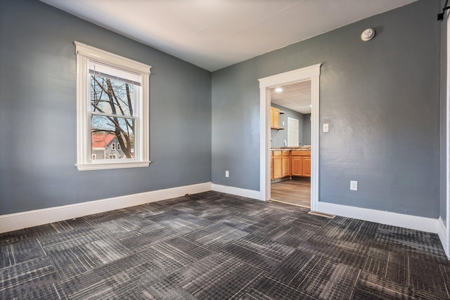 empty room featuring baseboards and dark carpet