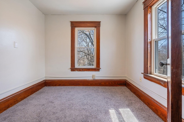 empty room featuring carpet floors, a healthy amount of sunlight, and baseboards