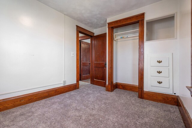 unfurnished bedroom with a closet, carpet flooring, and baseboards