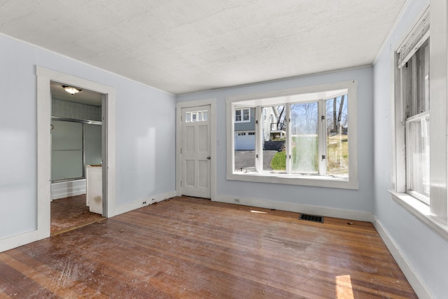interior space with hardwood / wood-style floors, visible vents, and baseboards