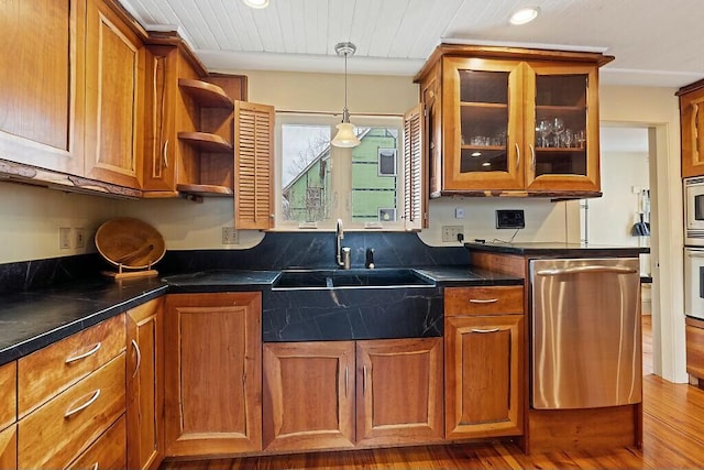 kitchen with glass insert cabinets, dark countertops, brown cabinets, and appliances with stainless steel finishes