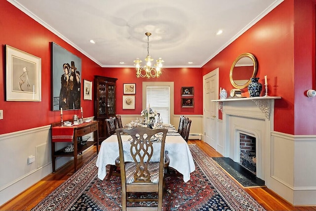 dining area featuring ornamental molding, wainscoting, wood finished floors, and a chandelier