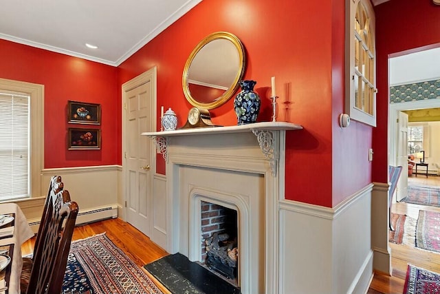 home office with a fireplace with flush hearth, crown molding, a baseboard radiator, wood finished floors, and wainscoting