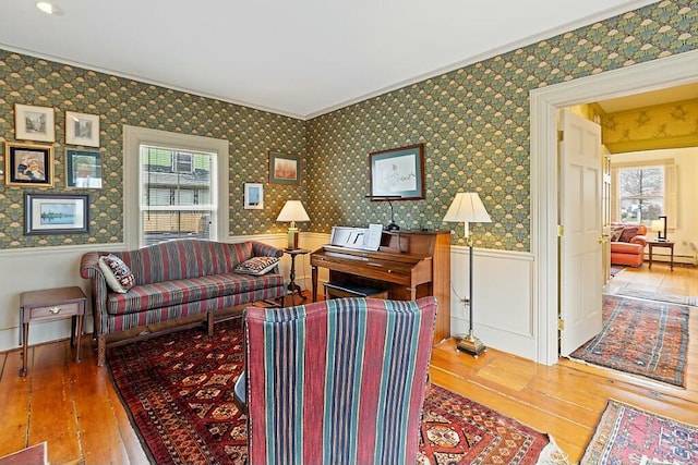 living room with a wainscoted wall, a healthy amount of sunlight, hardwood / wood-style flooring, and ornamental molding