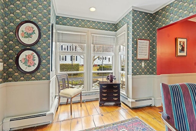 living area featuring a healthy amount of sunlight, wallpapered walls, ornamental molding, and a wainscoted wall