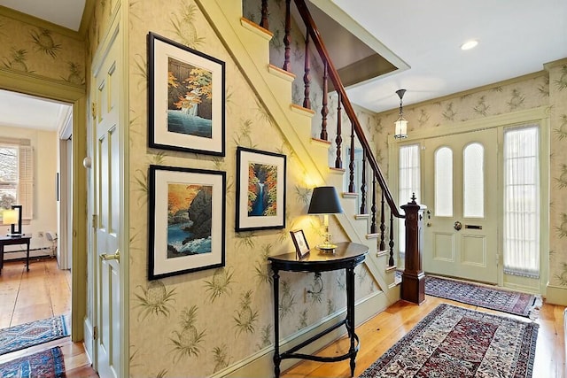 foyer entrance with baseboards, wallpapered walls, light wood-type flooring, and stairway