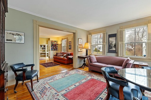 living area featuring baseboards, hardwood / wood-style flooring, and crown molding