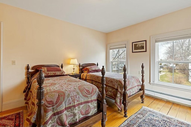 bedroom with light wood-style flooring, baseboard heating, and baseboards