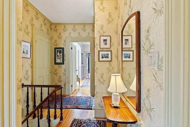 hallway featuring wood finished floors and wallpapered walls