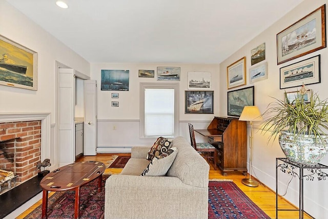 living room featuring a fireplace, recessed lighting, wood finished floors, and a baseboard radiator