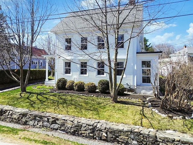 colonial home featuring a chimney and a front lawn