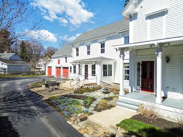 back of house with a garage, a residential view, driveway, and roof with shingles
