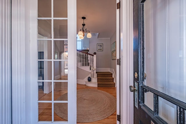entrance foyer with stairway, french doors, wood finished floors, and a chandelier