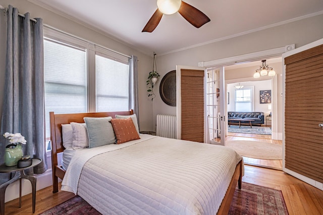 bedroom featuring ceiling fan, french doors, crown molding, wood finished floors, and radiator
