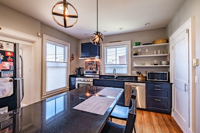 kitchen featuring a sink, appliances with stainless steel finishes, dark countertops, and a healthy amount of sunlight