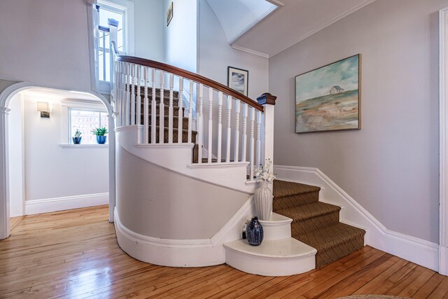 stairs with baseboards, arched walkways, and hardwood / wood-style flooring
