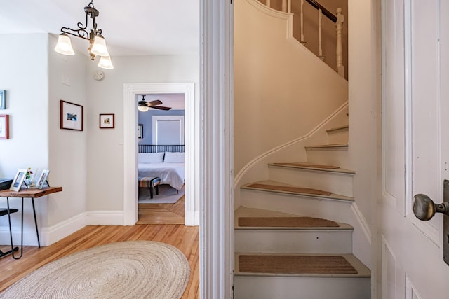stairway featuring baseboards, a ceiling fan, and wood finished floors