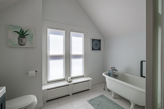 bathroom with toilet, tile patterned floors, baseboards, lofted ceiling, and a soaking tub