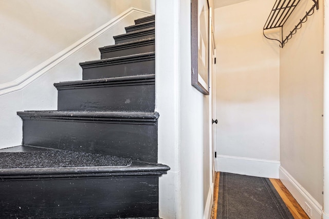 staircase with baseboards and wood finished floors