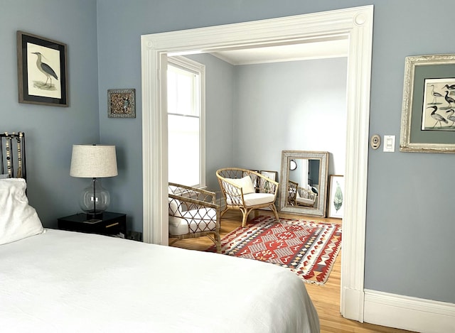 bedroom featuring ornamental molding, baseboards, and wood finished floors