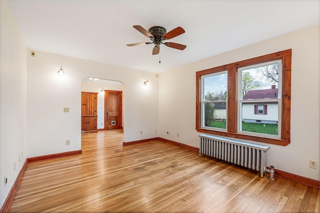 30 Munroe St, Bangor, ME 04401 - empty room with radiator heating unit, light wood-type flooring, a ceiling fan, baseboards, and arched walkways