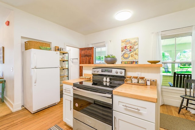 kitchen featuring butcher block countertops, freestanding refrigerator, open shelves, and stainless steel electric range oven