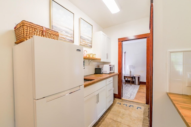 kitchen featuring light wood finished floors, white cabinetry, white appliances, open shelves, and butcher block counters