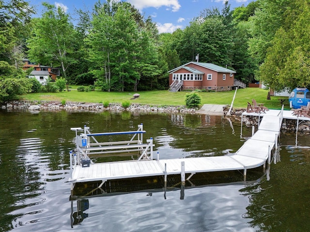 dock area with a wooded view, a yard, and a water view