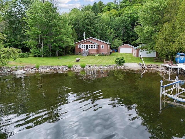 view of dock with a wooded view, a yard, and a water view
