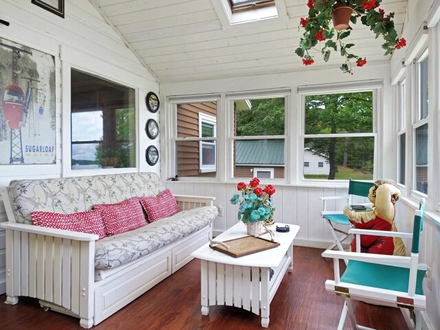 sunroom / solarium featuring wooden walls, lofted ceiling with skylight, and wood finished floors