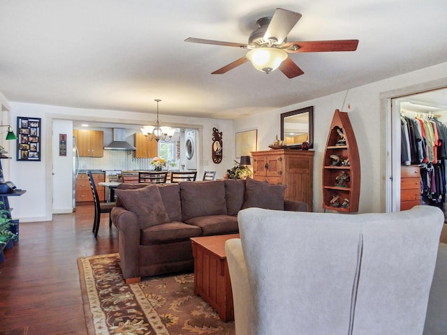 living room featuring dark wood finished floors, ceiling fan with notable chandelier, and stacked washer / drying machine