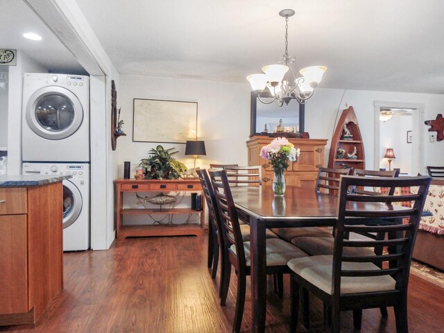 dining area with stacked washer / drying machine, a notable chandelier, and dark wood finished floors