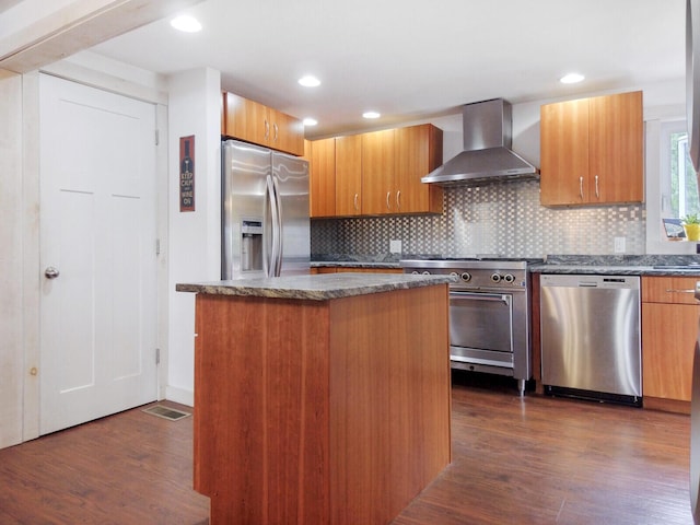 kitchen featuring wall chimney exhaust hood, dark wood-style flooring, appliances with stainless steel finishes, and decorative backsplash
