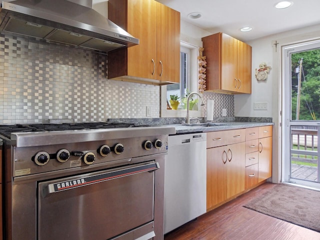 kitchen featuring a sink, stainless steel appliances, dark wood-style floors, extractor fan, and backsplash