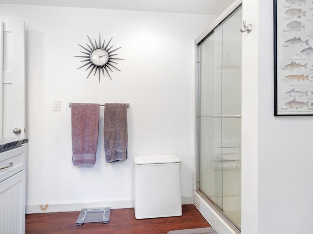 bathroom featuring wood finished floors, vanity, and a stall shower
