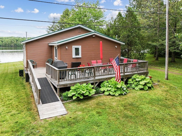 back of house with a deck with water view and a lawn