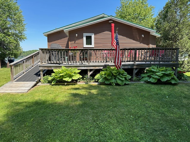 rear view of house featuring a deck and a yard
