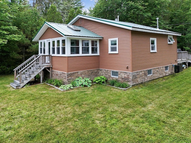 view of home's exterior with stairs, metal roof, a yard, and stone siding