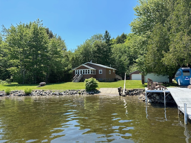 view of dock with a yard, a water view, and a wooded view