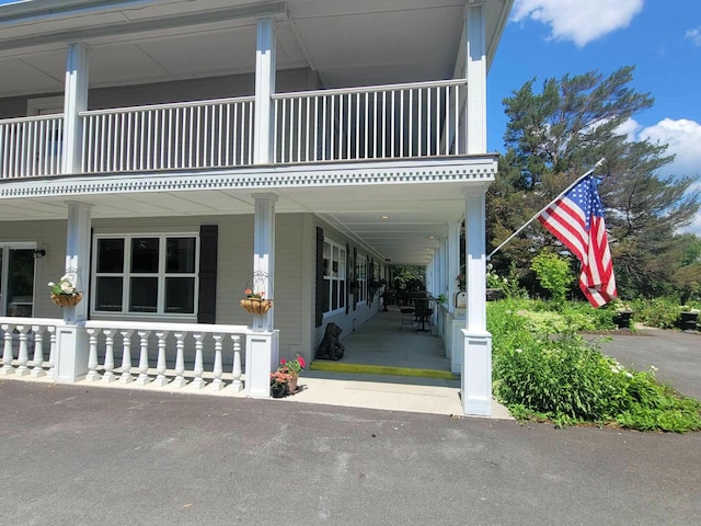 view of property exterior featuring a porch and a balcony