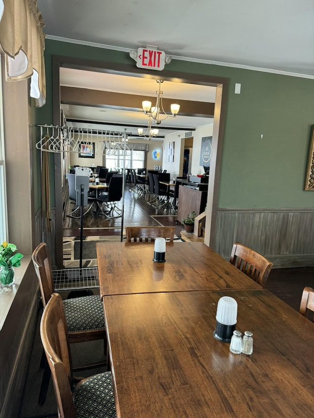 dining space with wainscoting, ornamental molding, and an inviting chandelier