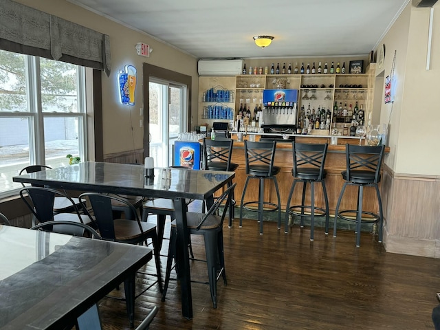 dining room featuring wood finished floors, ornamental molding, a wall unit AC, and a community bar