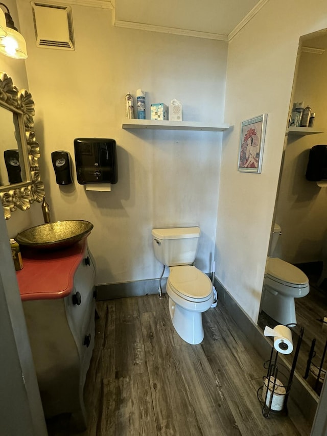 bathroom featuring wood finished floors, vanity, ornamental molding, and toilet