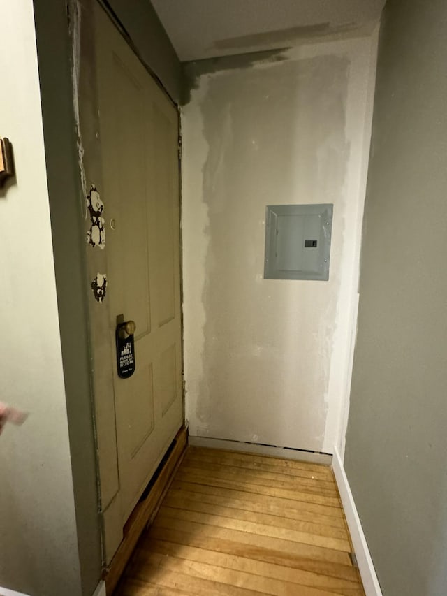 hall with electric panel, baseboards, and light wood-style floors