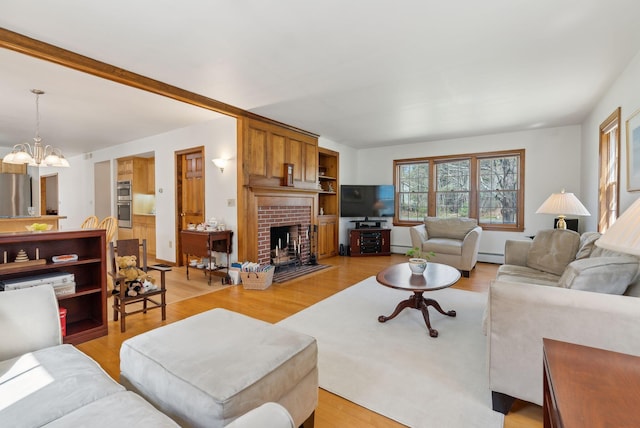 19 Windsor Pines Dr, Scarborough, ME 04074 - living area featuring a chandelier, a baseboard radiator, light wood finished floors, and a brick fireplace