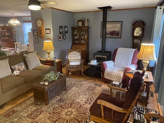 living room with wood finished floors, a wood stove, and crown molding