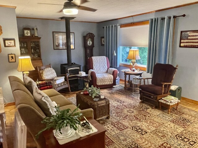 living area with baseboards, a ceiling fan, ornamental molding, and a wood stove